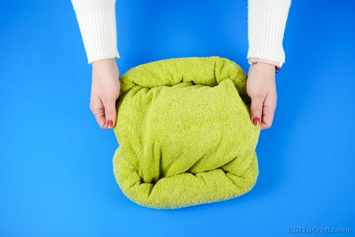 Twisting green towel into square