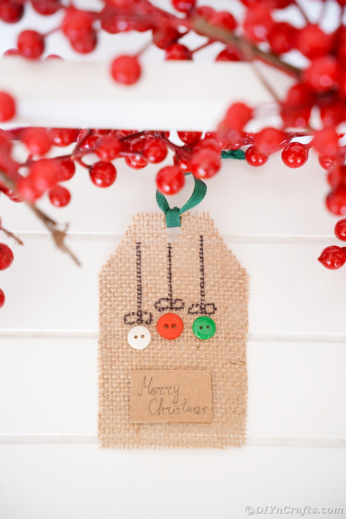 Burlap gift tag with buttons hanging against white shiplap wall