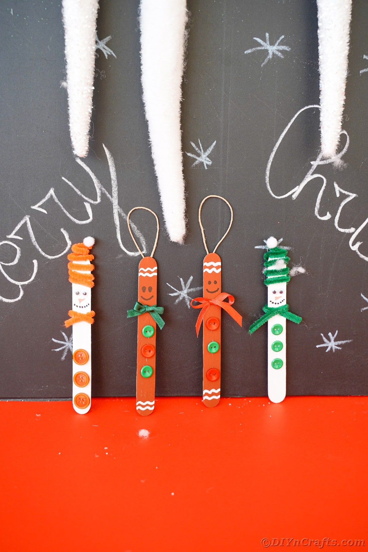 four craft stick ornaments against chalkboard