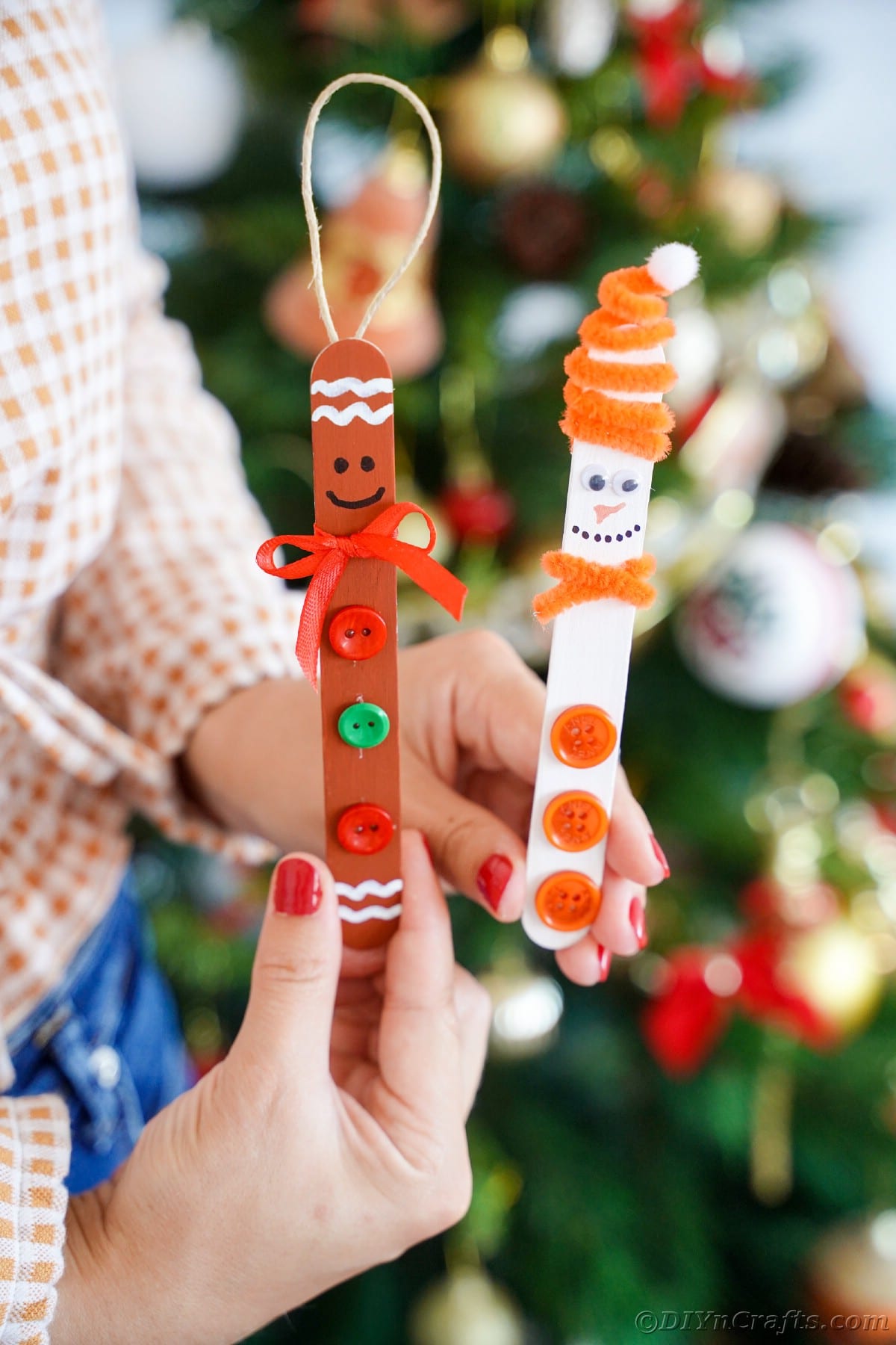 woman holding a gingerbread and snowman craft stick ornament