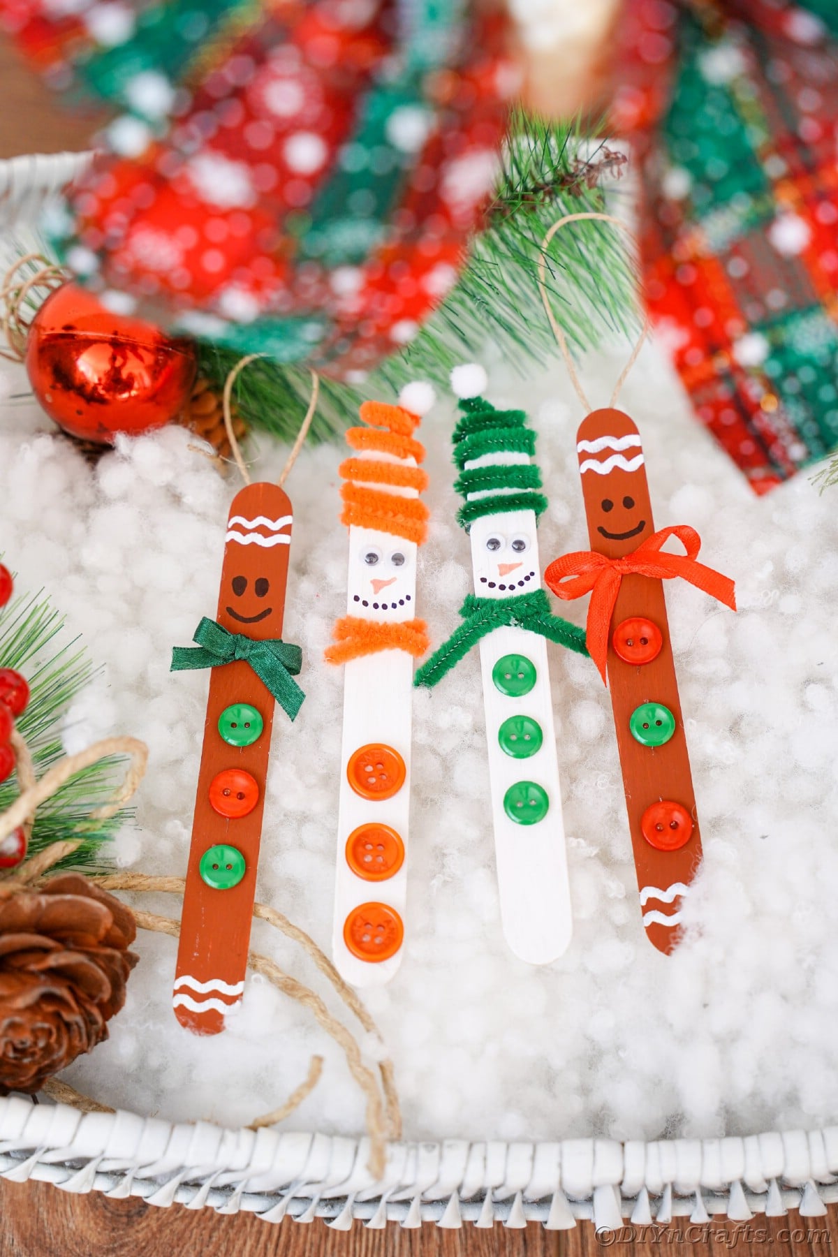 four craft stick ornaments on fake snow