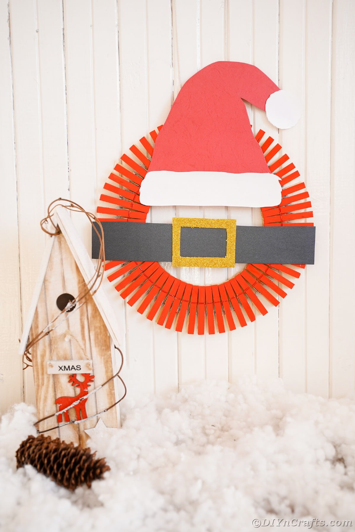 santa hat wreath hanging on white shiplap wall