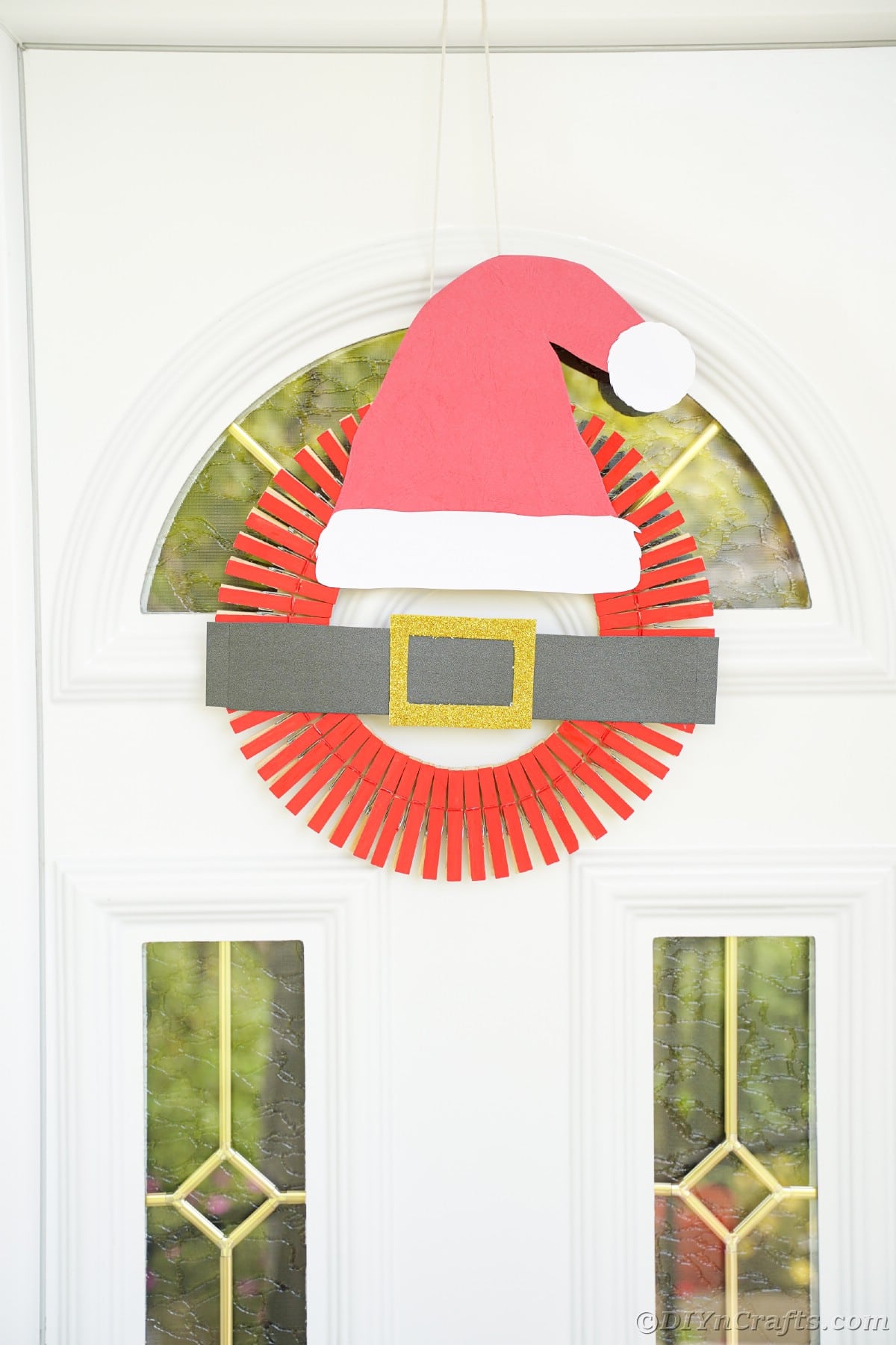 santa hat wreath hanging on white door with glass panels