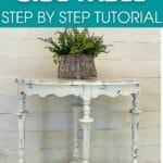 Basket of greenery on top of distressed white side table