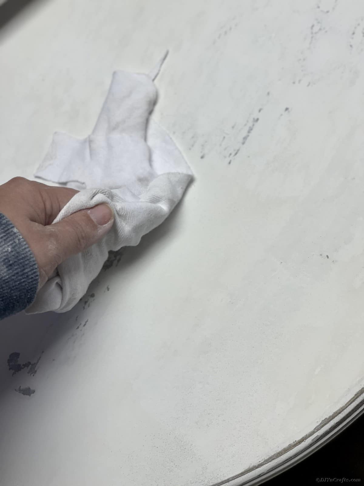 White cloth being wiped over top of white table