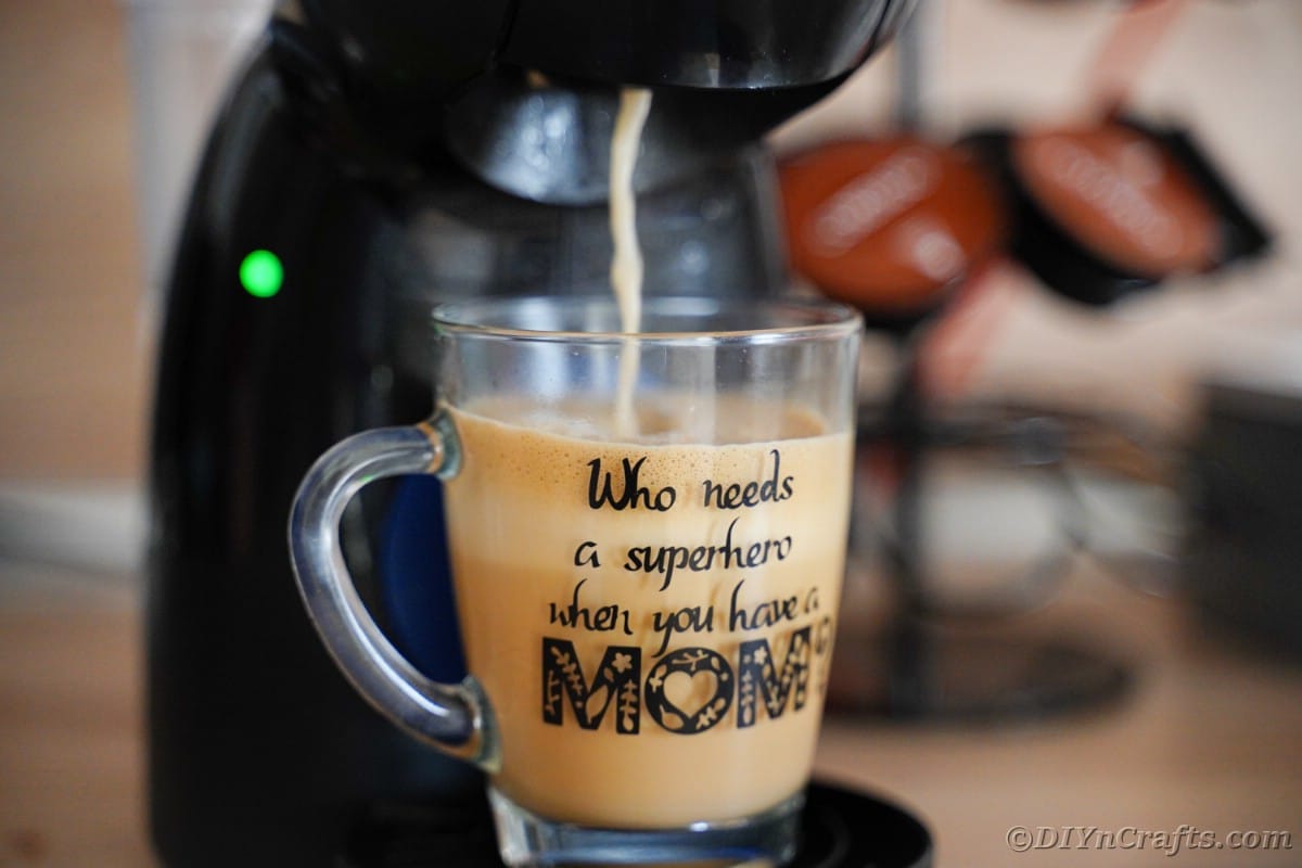 Glasbecherfüllung mit Kaffee unter Kaffeekanne