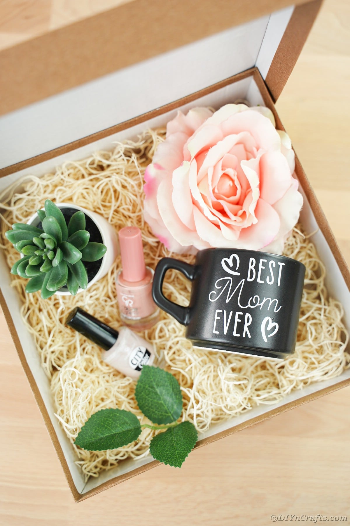Large box with fake hay and flowers nail polish and a black mothers day mug