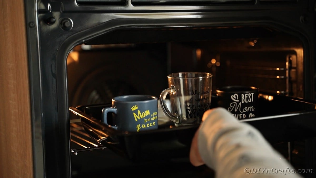Placing mugs into oven to cure