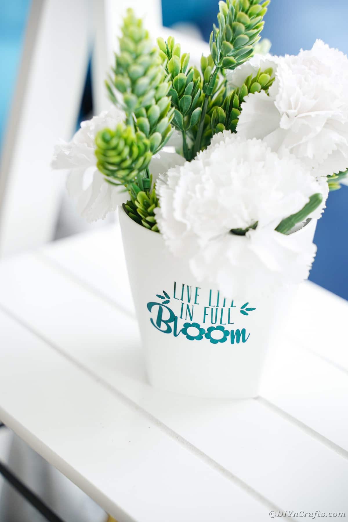 White bucket on shelf with teal lettering