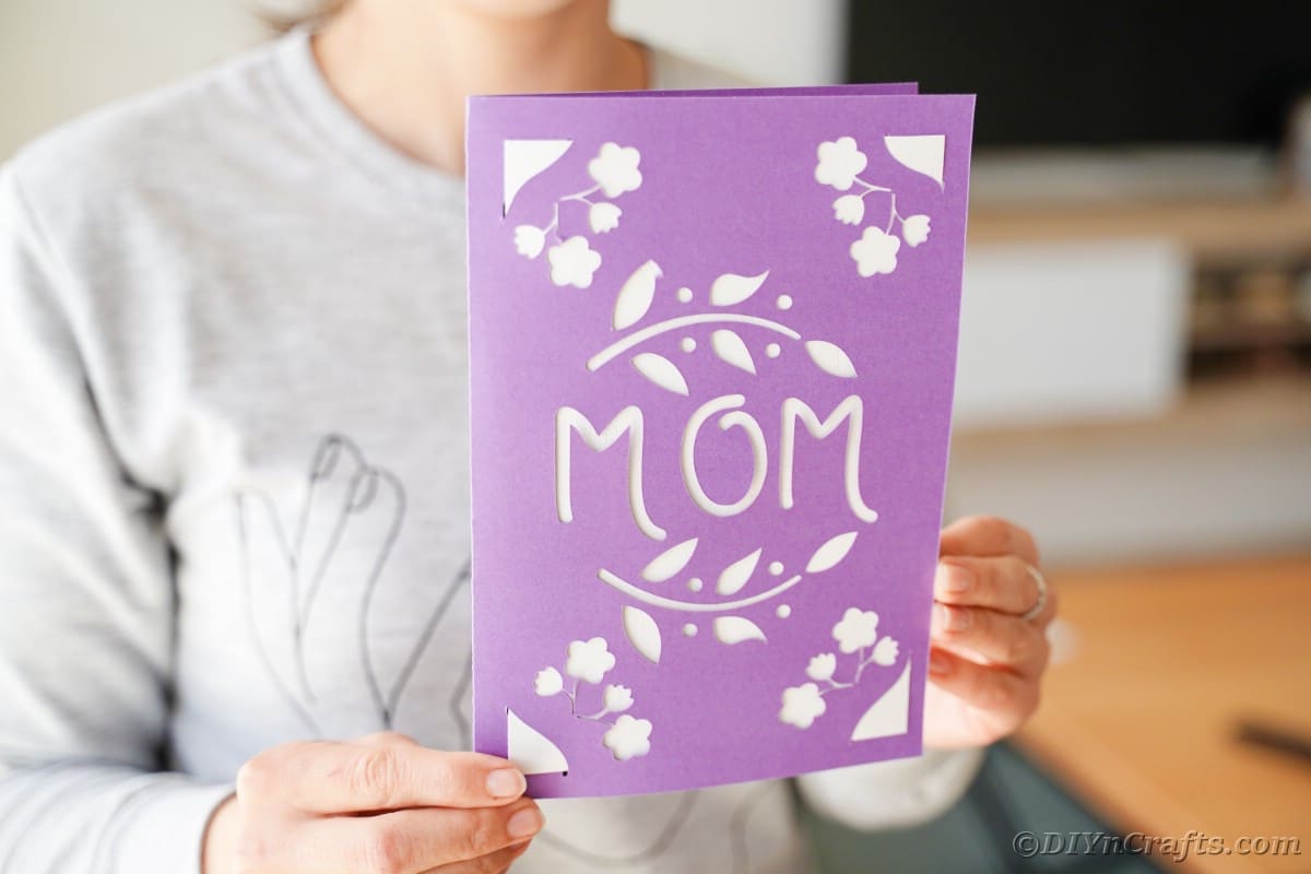Woman holding purple and white card that has mom stenciled on front