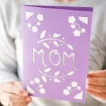 Woman holding purple card that says mom