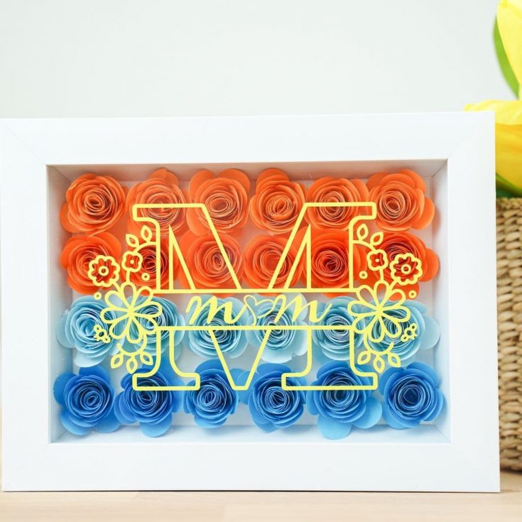 White shadowbox with colorful flowers on table