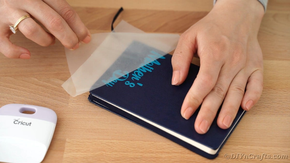 Woman peeling transfer tape off of blue book