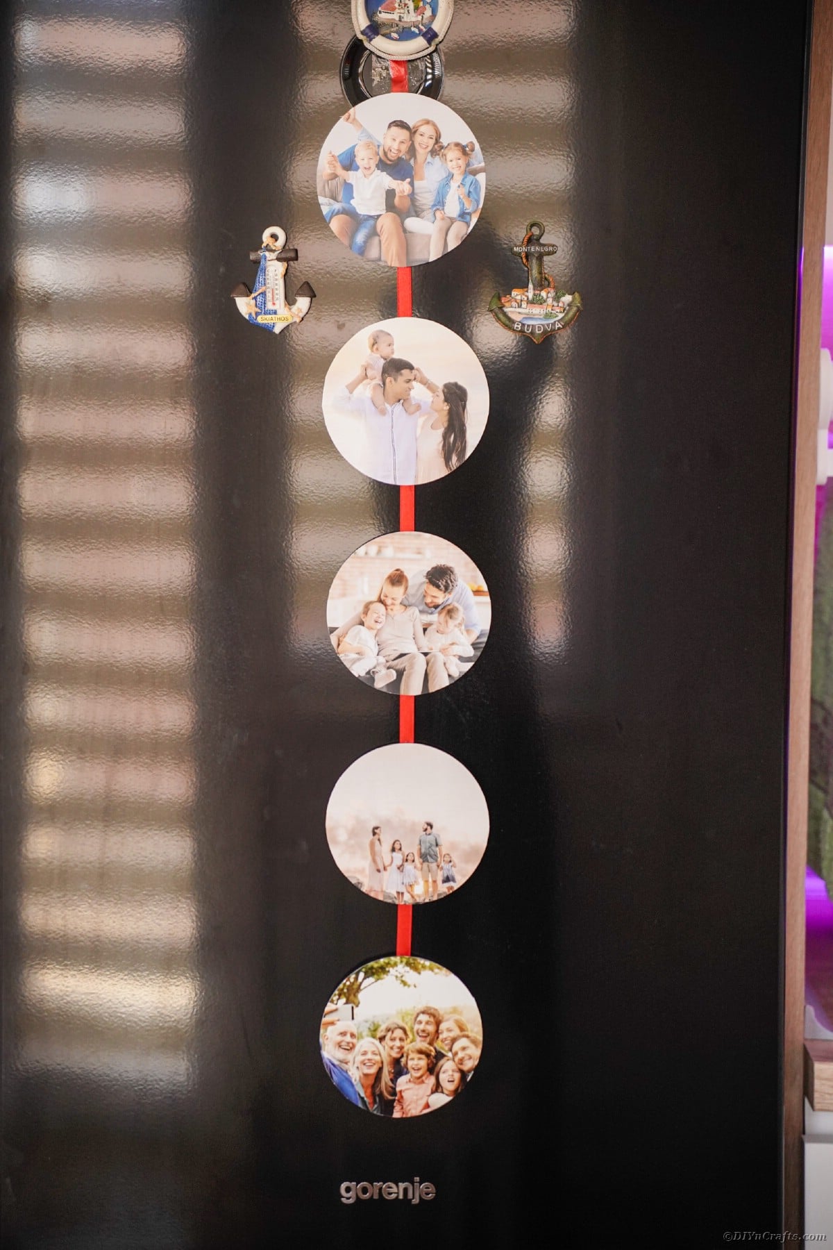 Photo ribbon with red ribbon hung on refrigerator with magnets