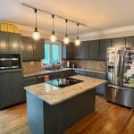 Renovated kitchen with gray cabinets and marbled counters on island