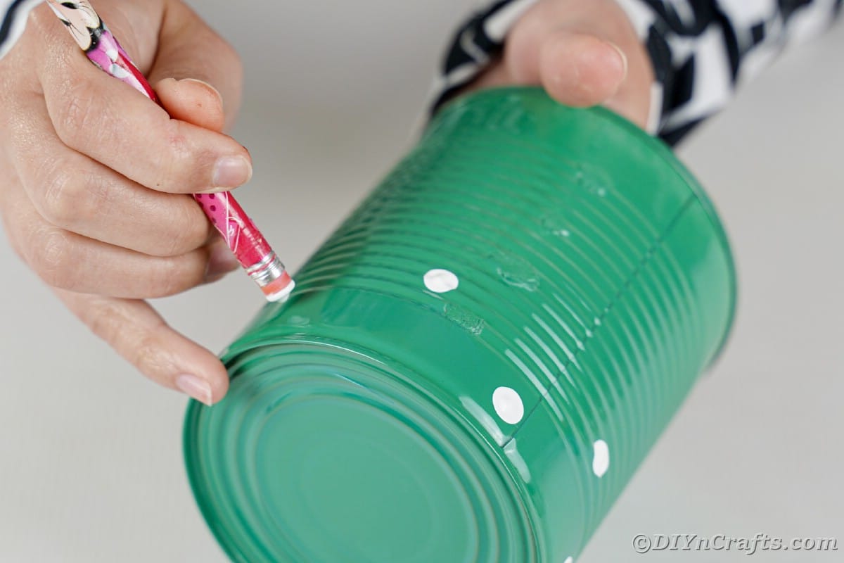 Painting white dots on green tin can
