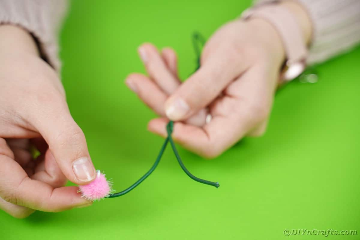 Gluing pink pom pom onto end of floral wire