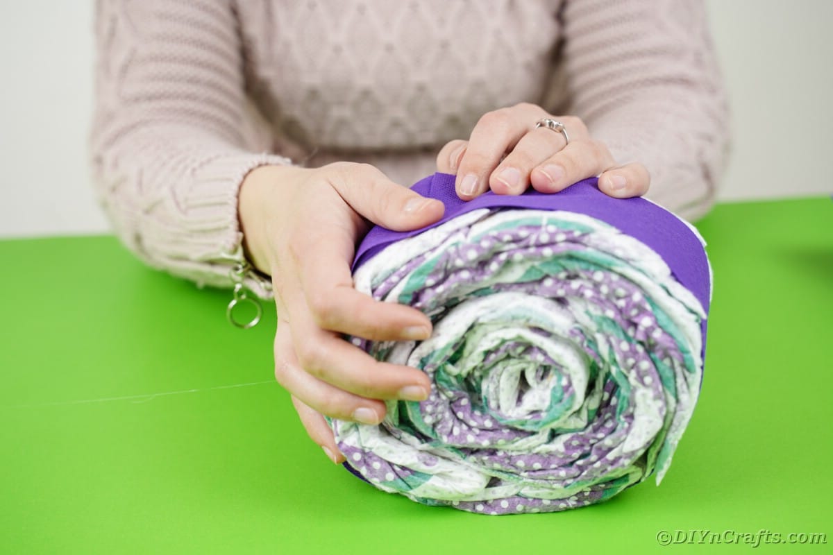Wrapping rolled diaper in purple paper