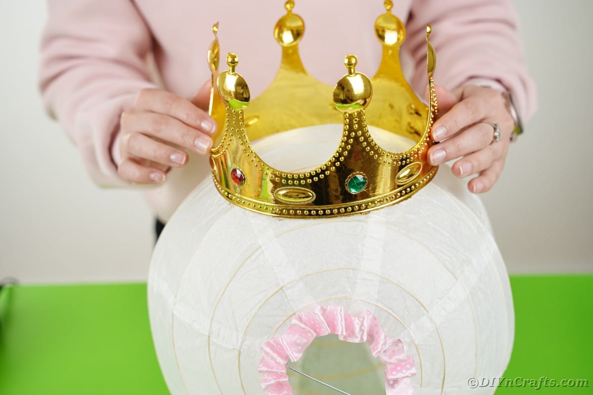 Fake crown being placed on top of white paper lantern