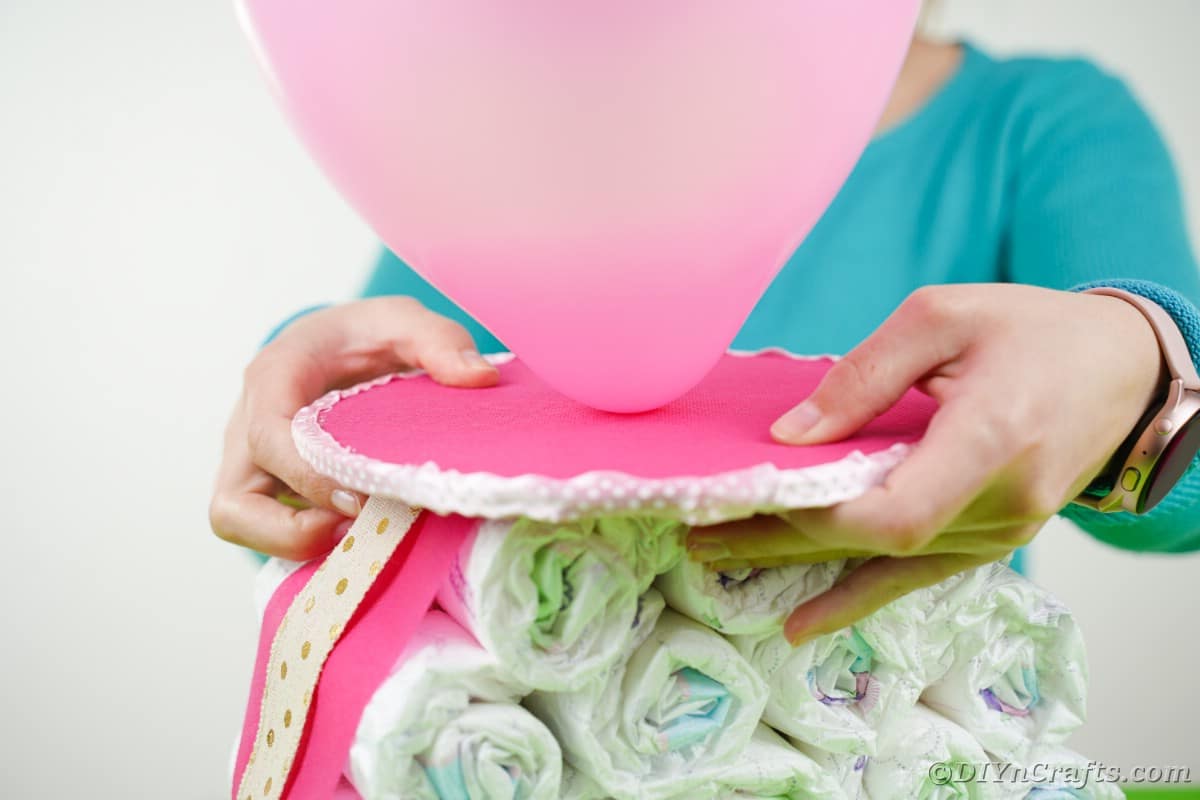 Woman placing balloon top on stack o diapers