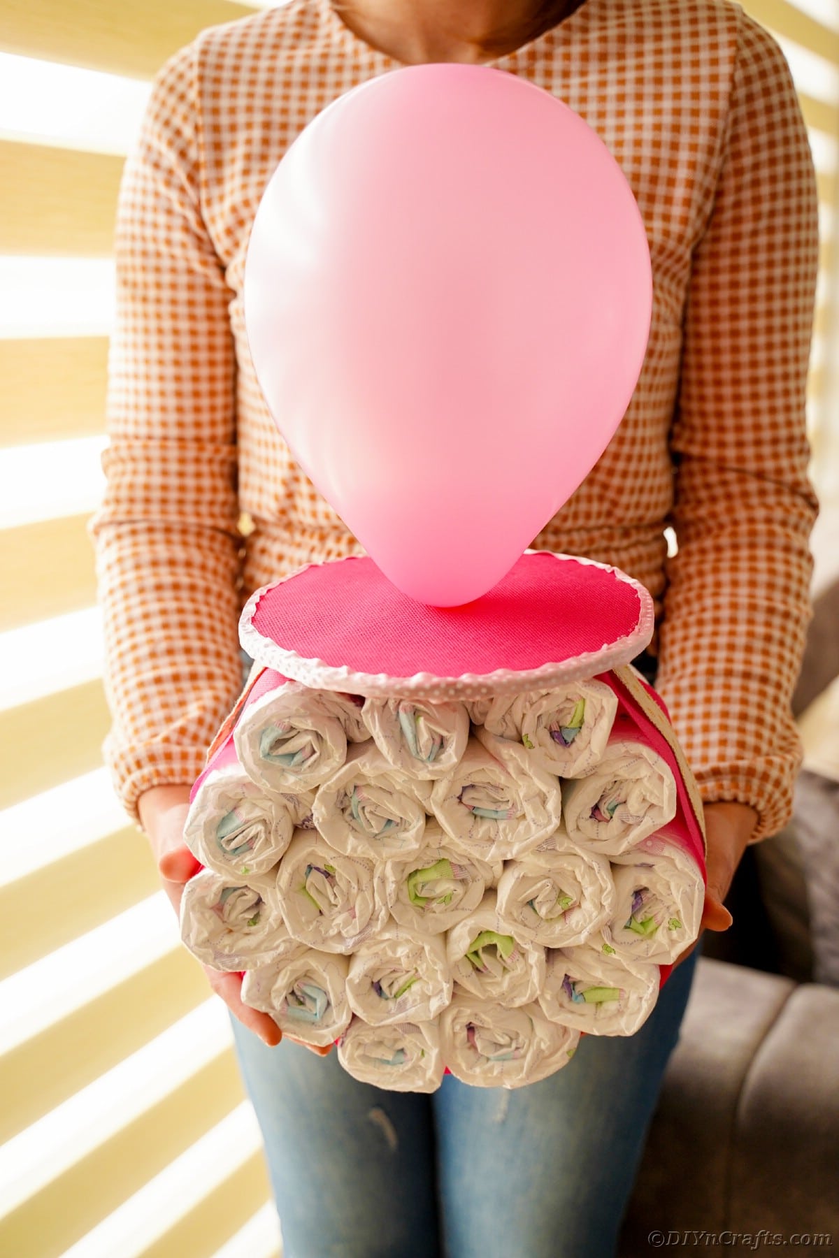Woman holding pink balloon diaper cake 