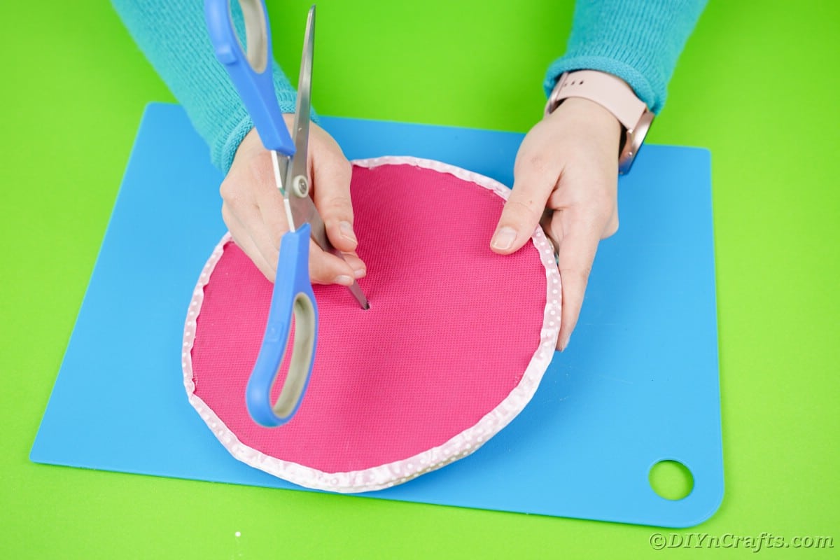 Using scissors to cut hole in middle of pink circle