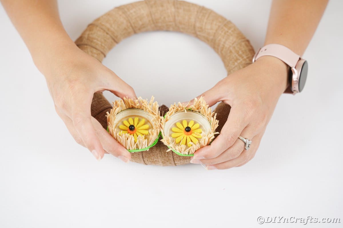 Hands gluing eyes to owl wreath