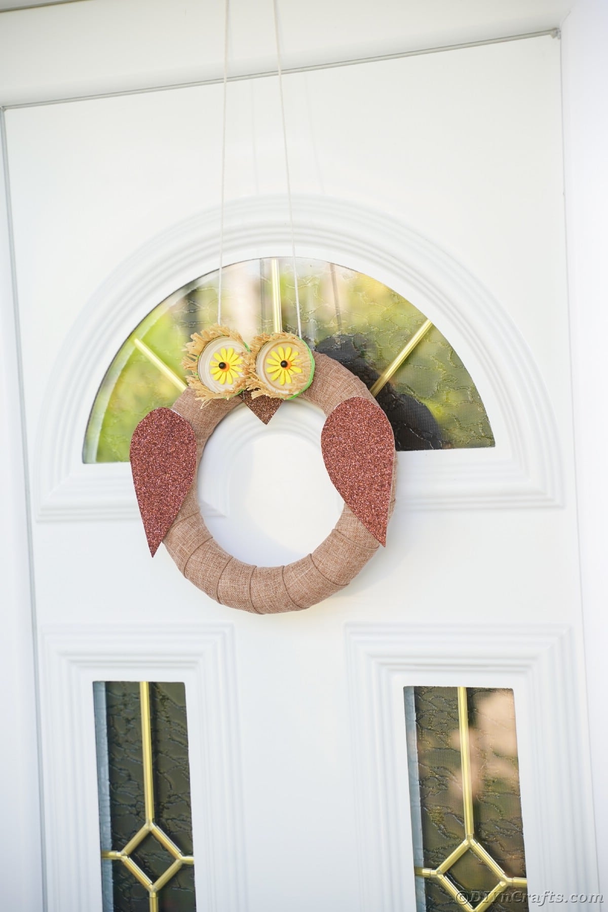 White door with glass panels holding owl wreath
