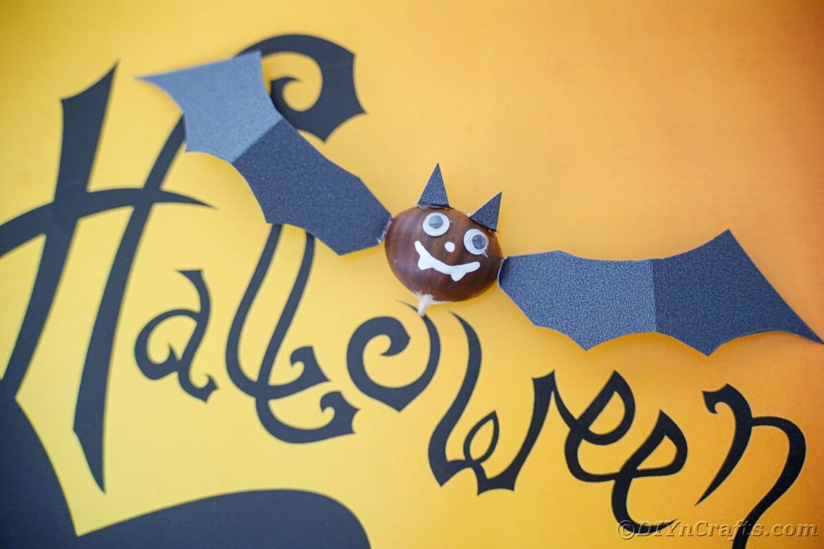 Yellow paper with black word Halloween holding bat decoration