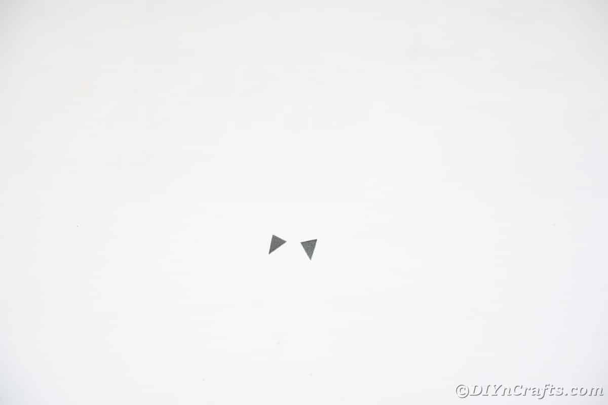 Tiny black triangles of paper on white table