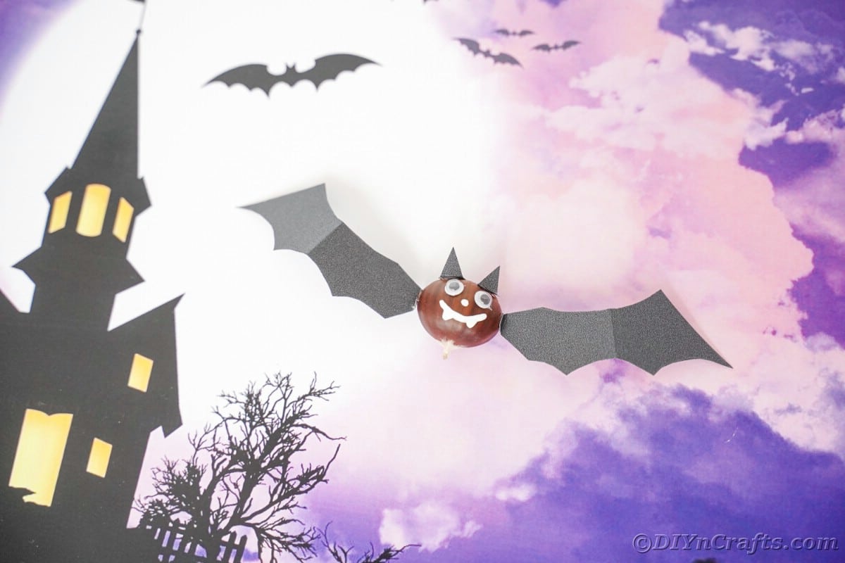 Purple halloween background under crafted chestnut bat