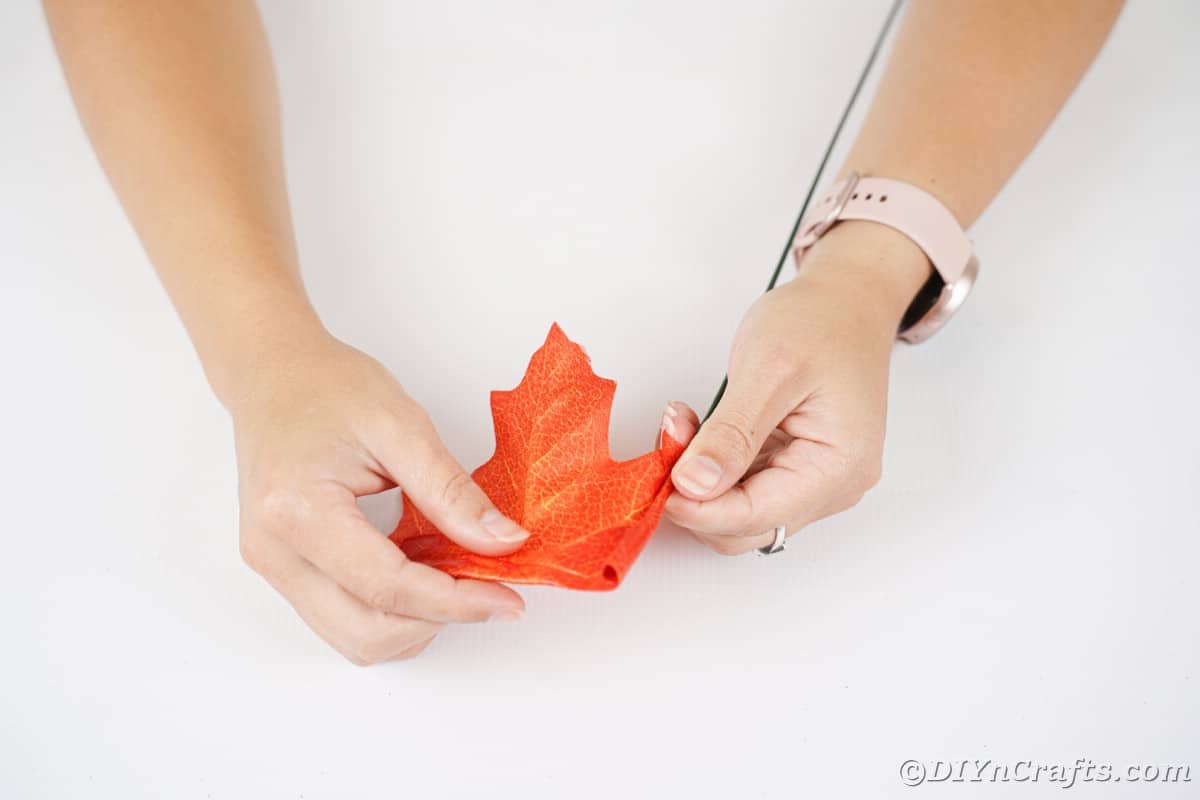 Hand rolling orange leaf over floral wire