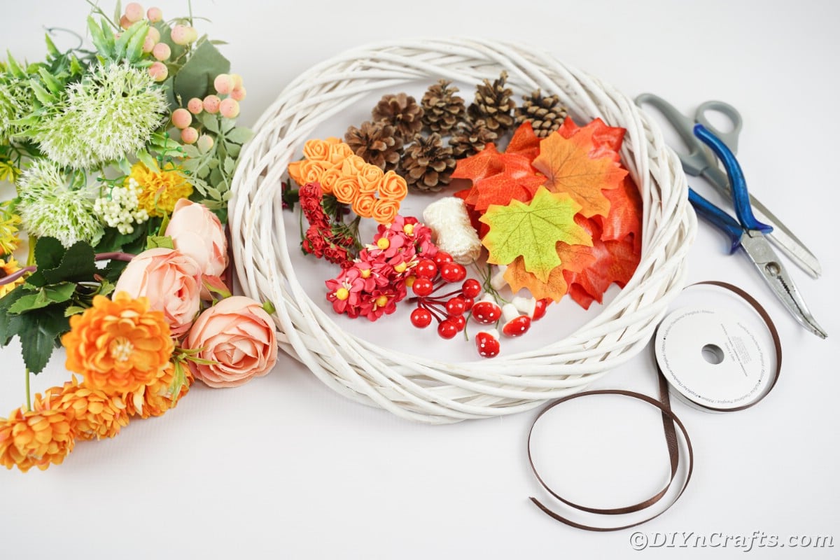 White wreath on table with ribbon and fake fall flowers