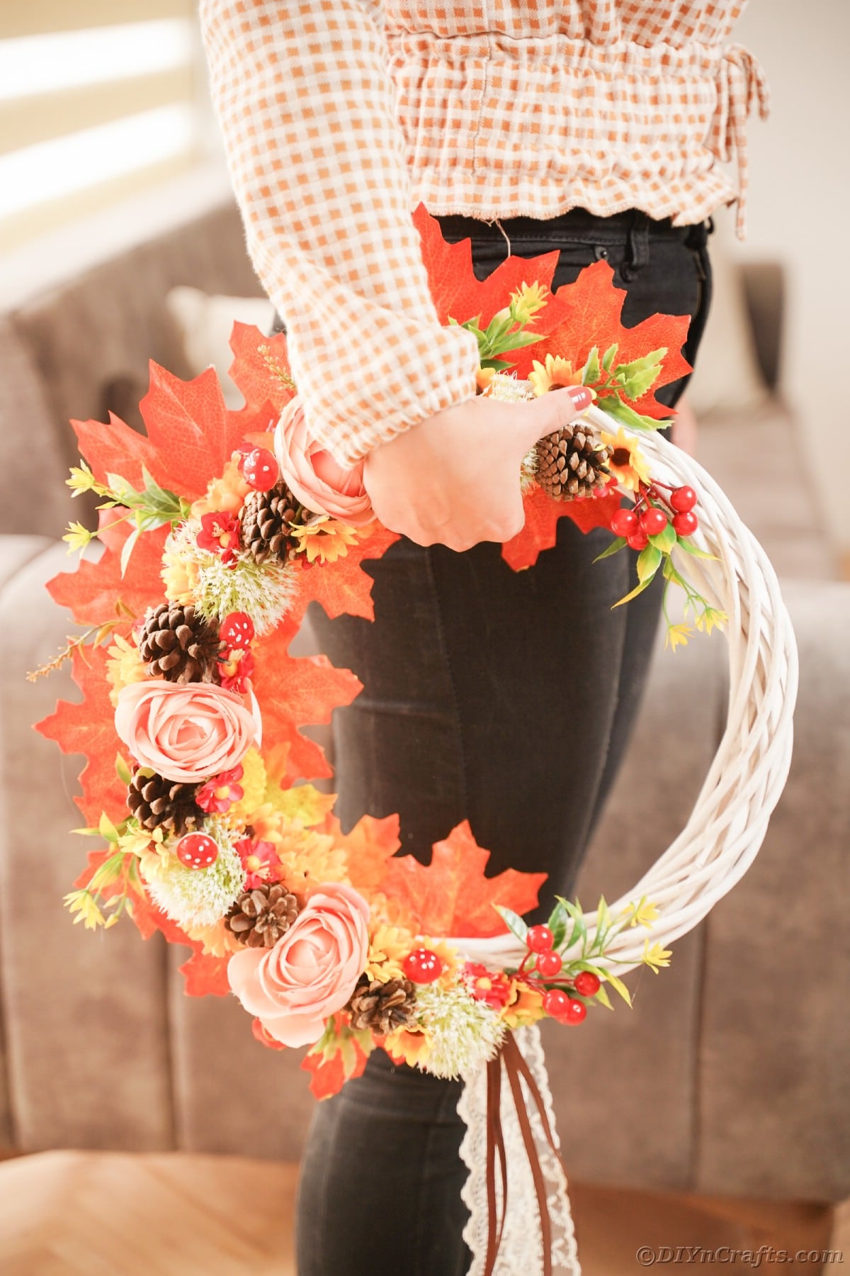 Fall wreath being held on the side by woman in black pants