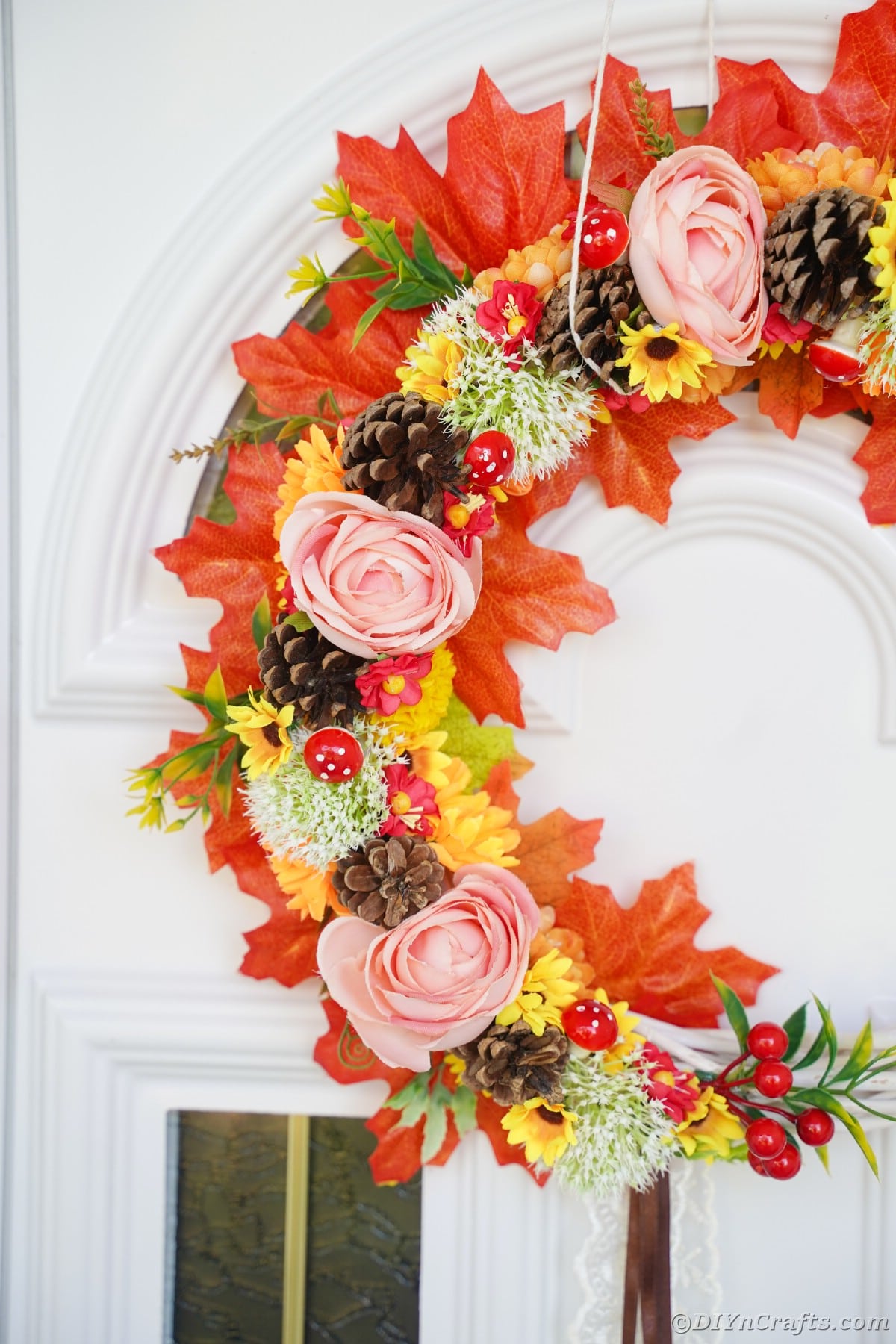Close up picture of floral and fall leaf wreath on white door