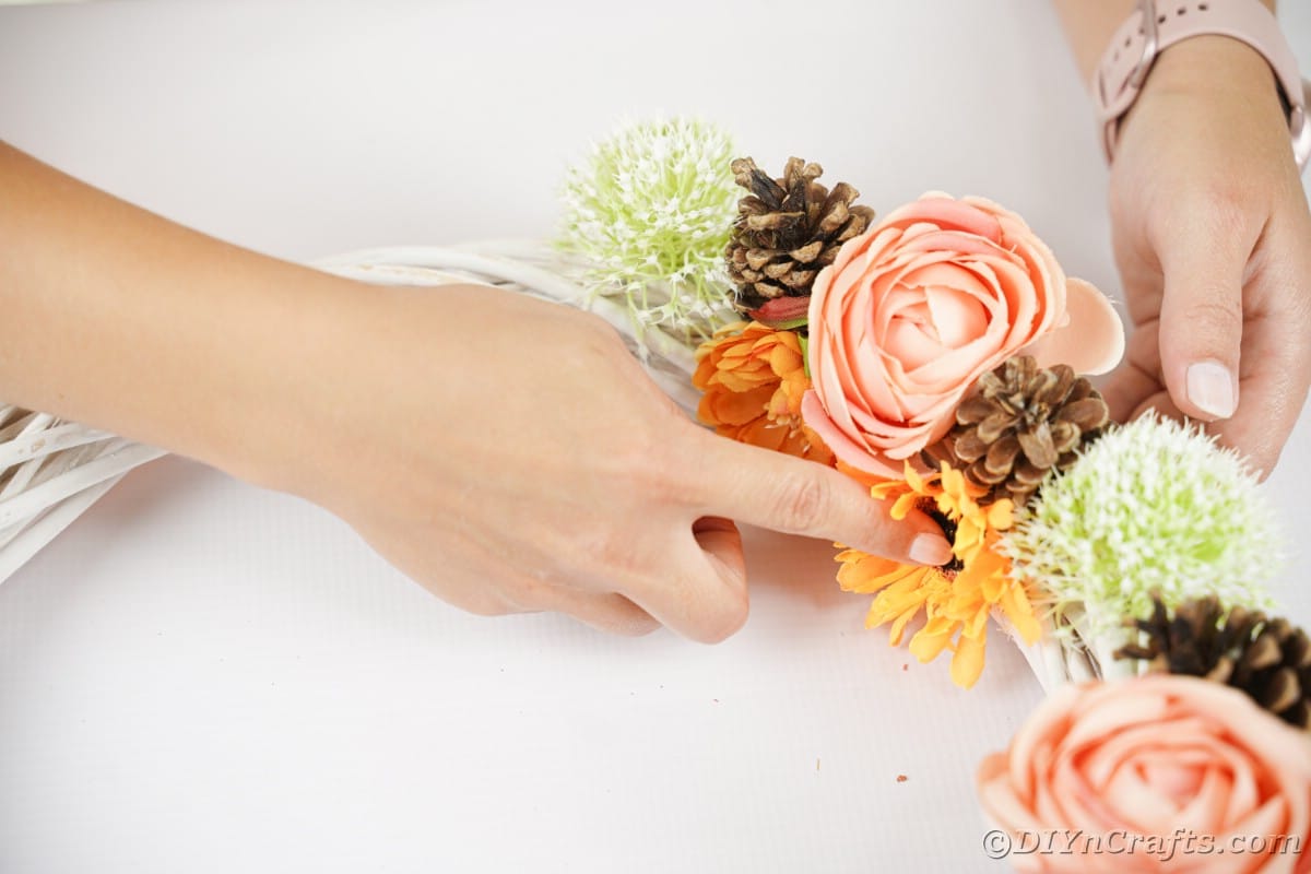 Hands holding flowers in place on wreath