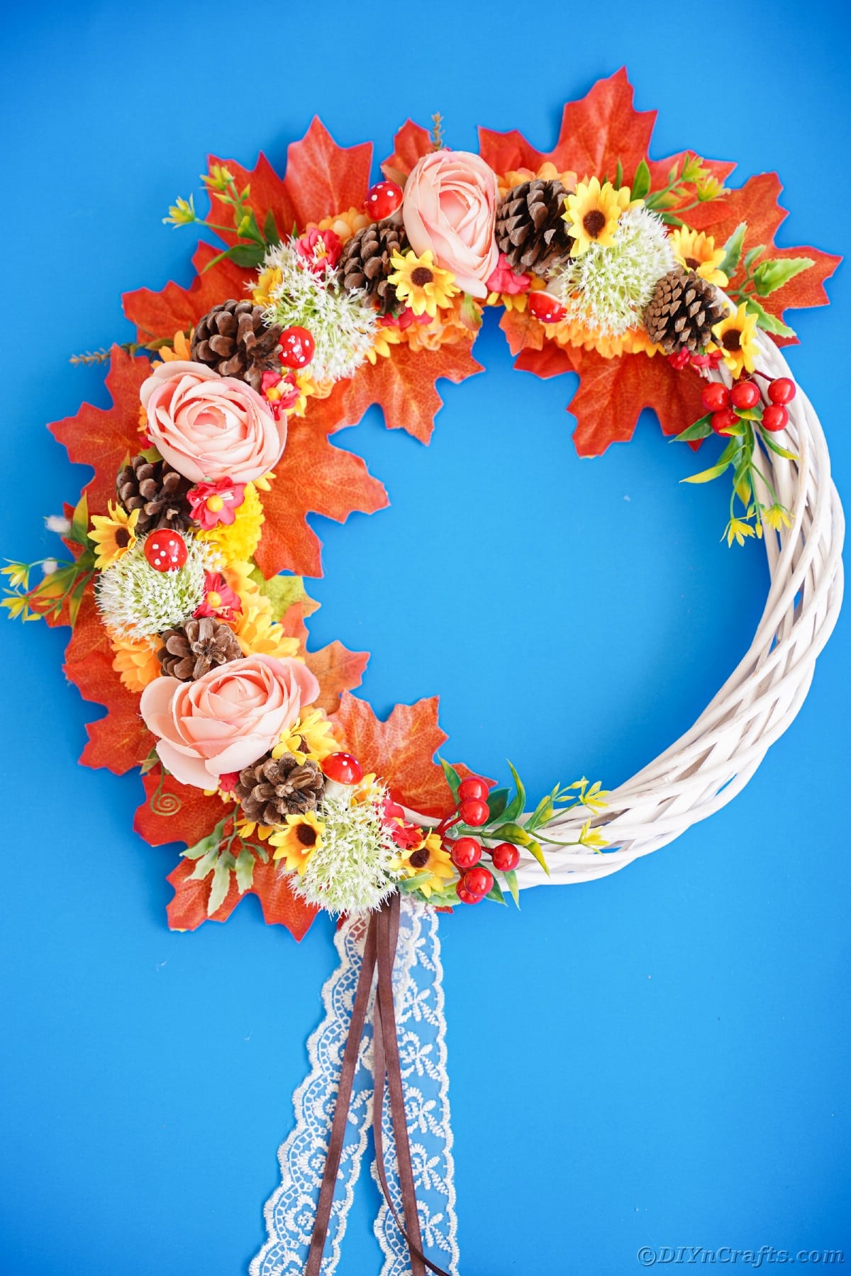 White grapevine wreath with fake leaves and flowers