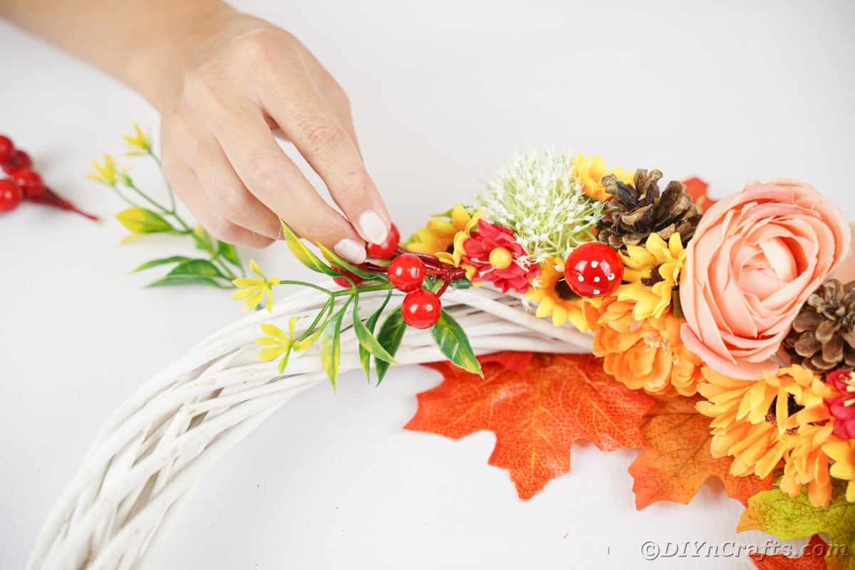 Hand putting berries onto wreath