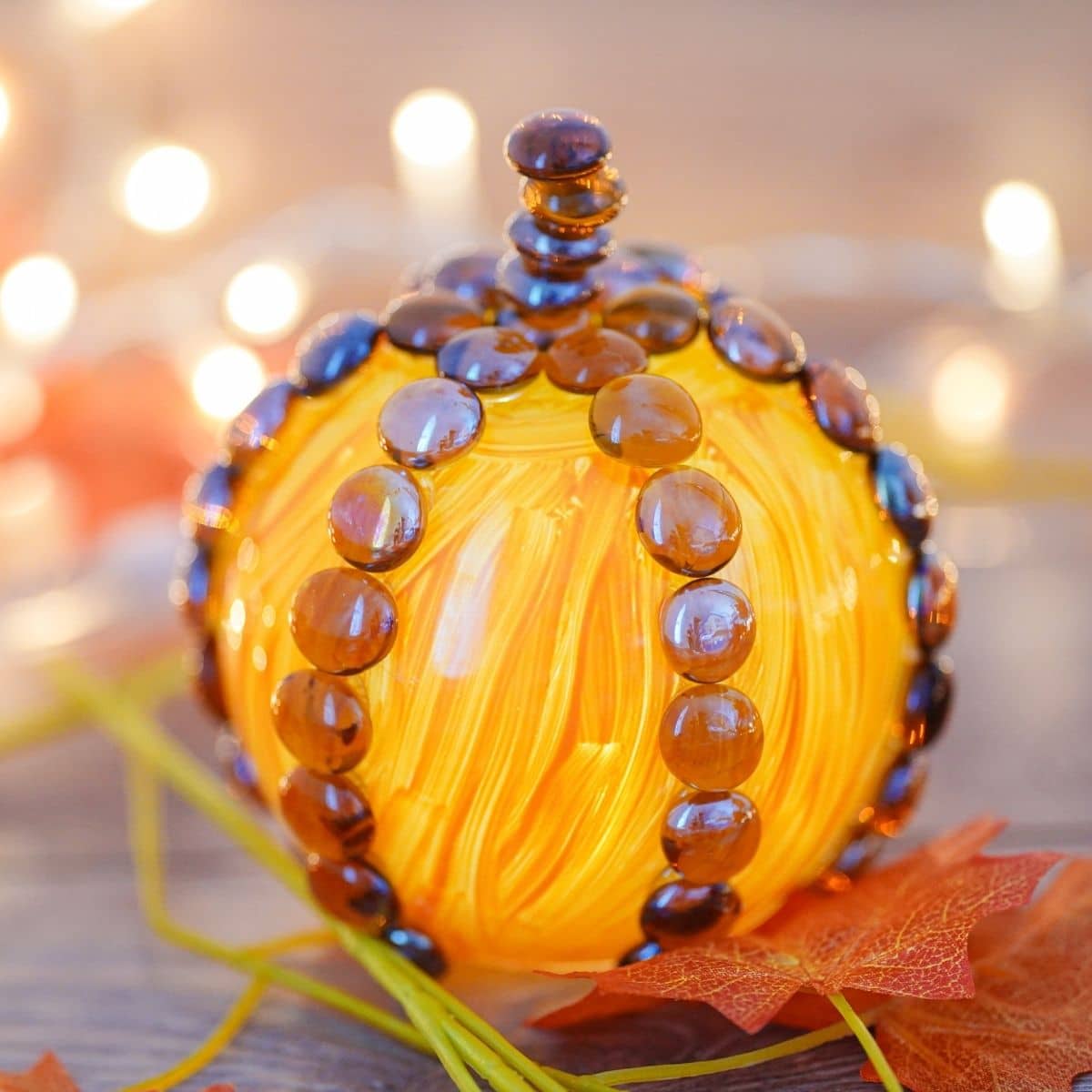Fake pumpkin on table with twinkle lights in background