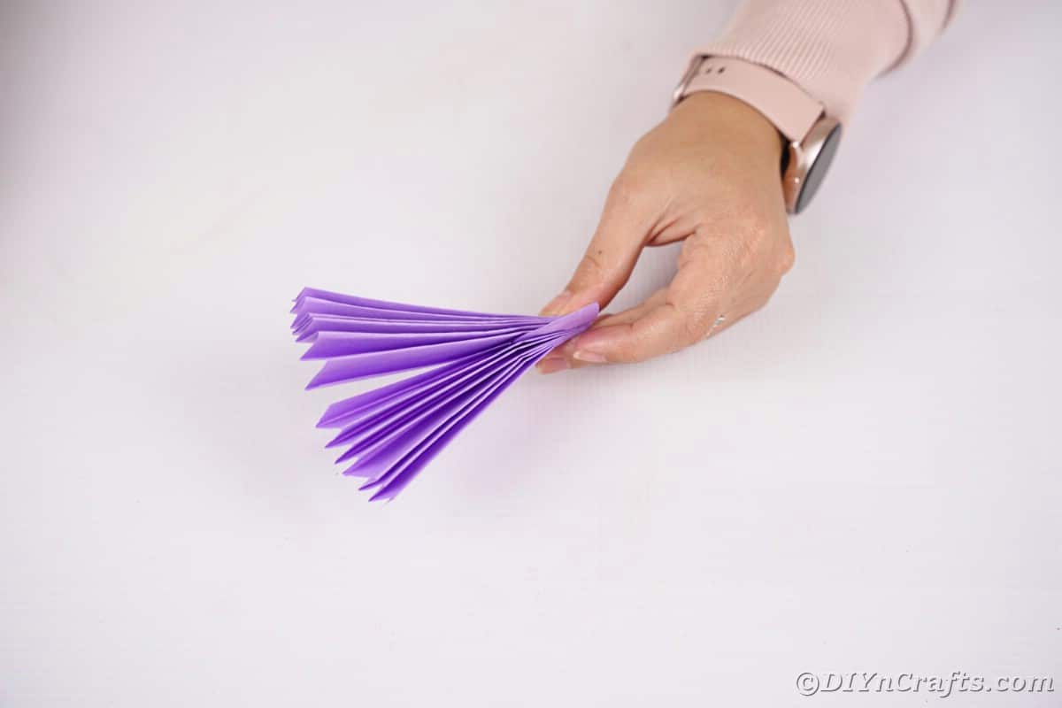 Frauenhand hält lila Papierfächer