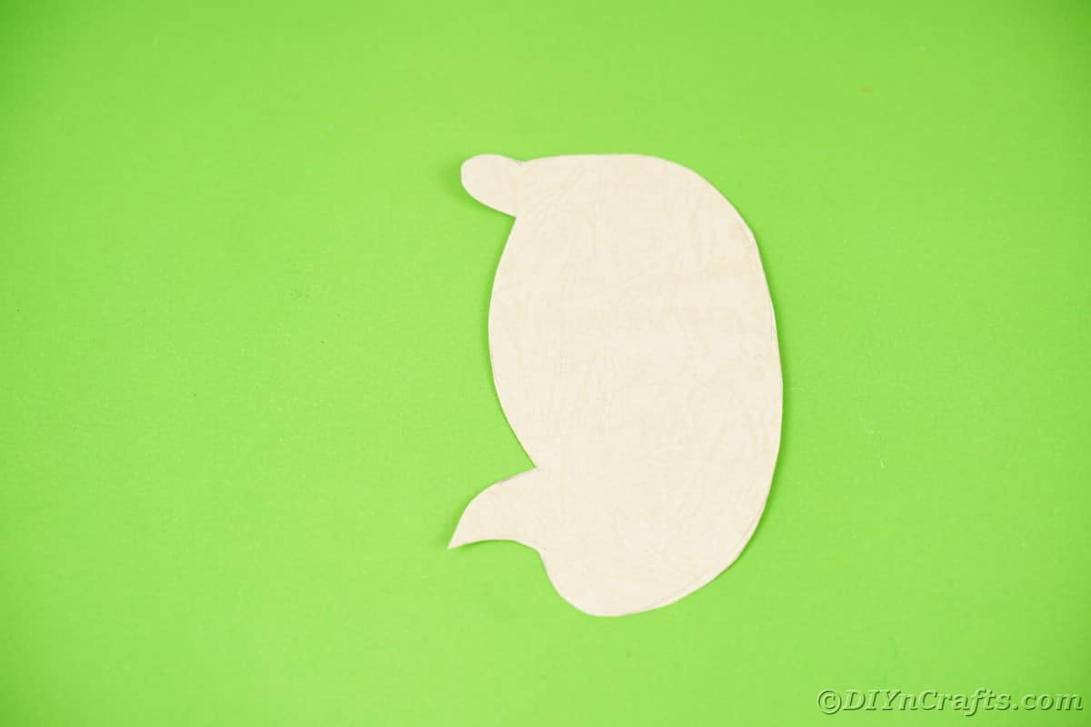 Cream paper hedgehog body shape on green surface