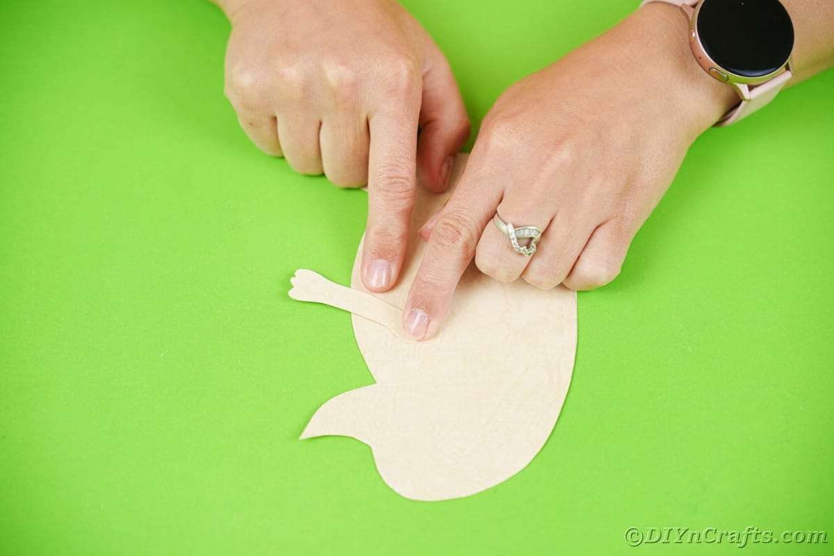 Fingers holding arm shaped paper on side of hedgehog shaped paper