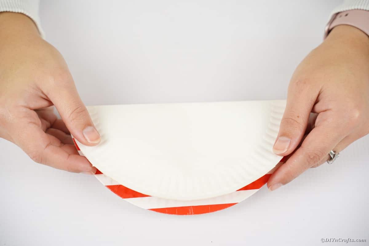 Hands folding paper plate in half