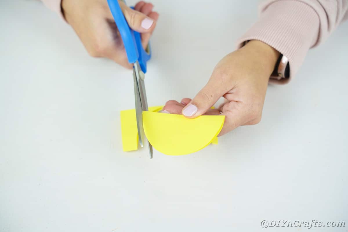 Gelbes halbmondförmiges Papier, das mit einer blauen Schere beschnitten wird