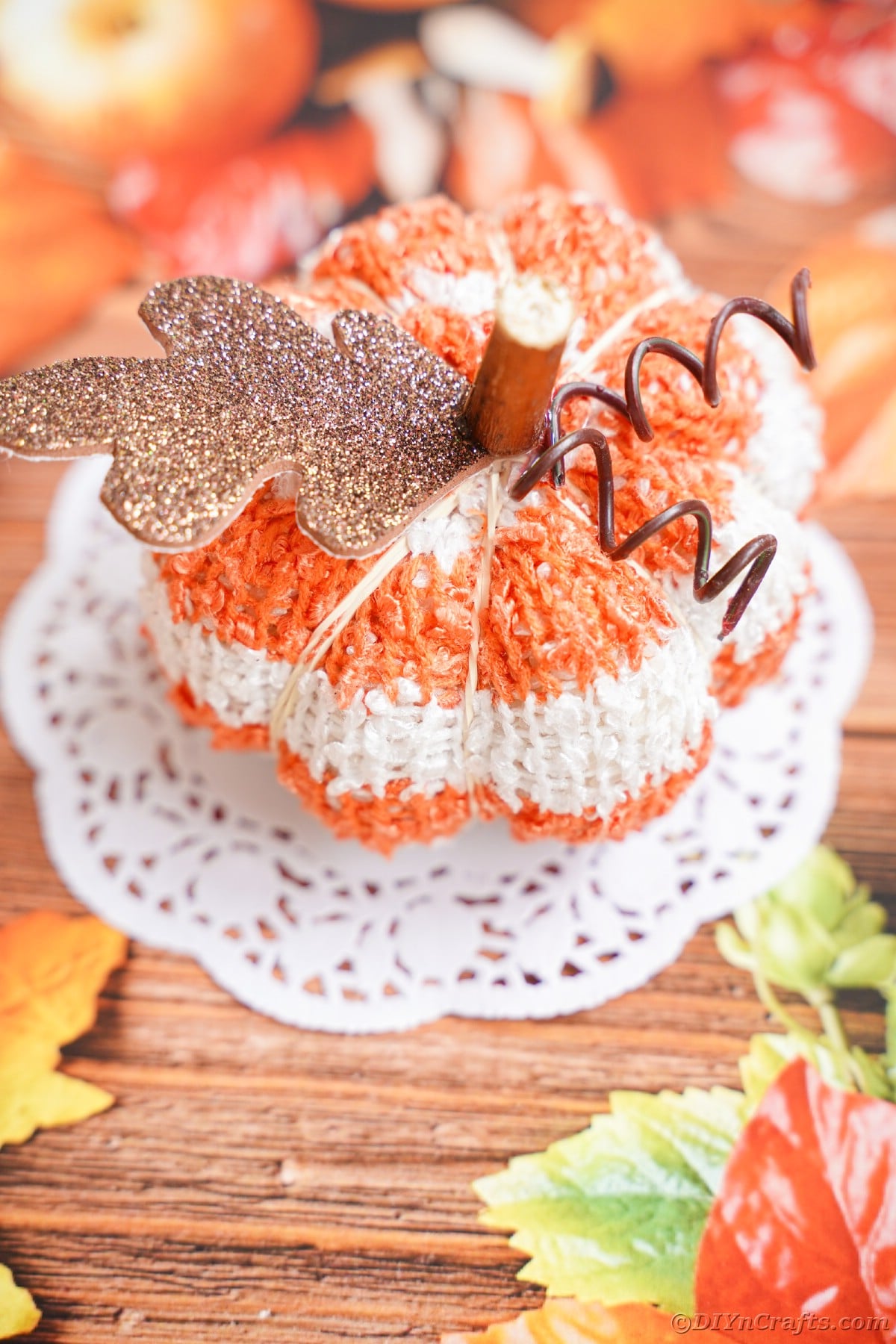 Seasonal paper topped with white doily and striped pumpkin