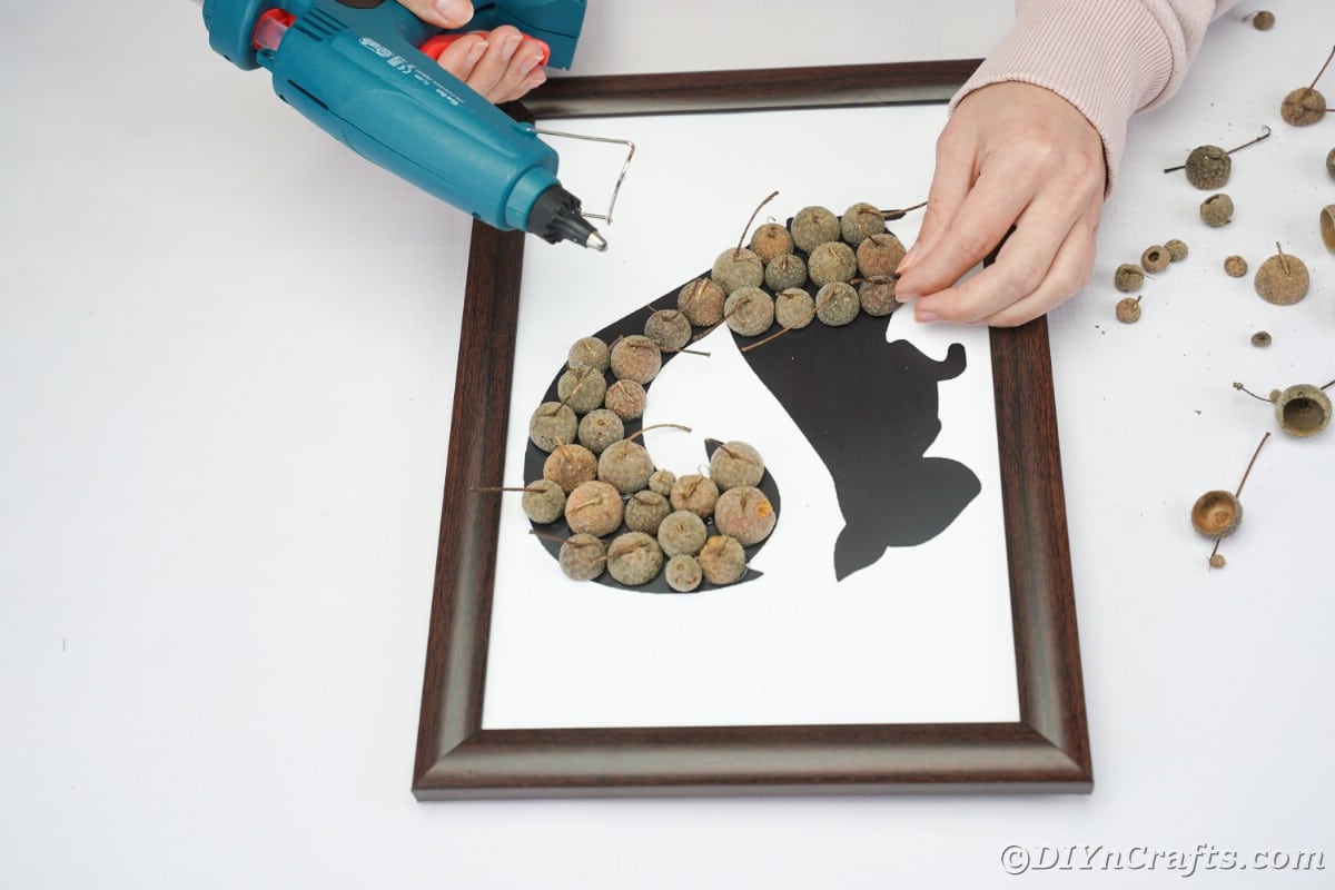 Hands adding acorn caps to printed template in frame