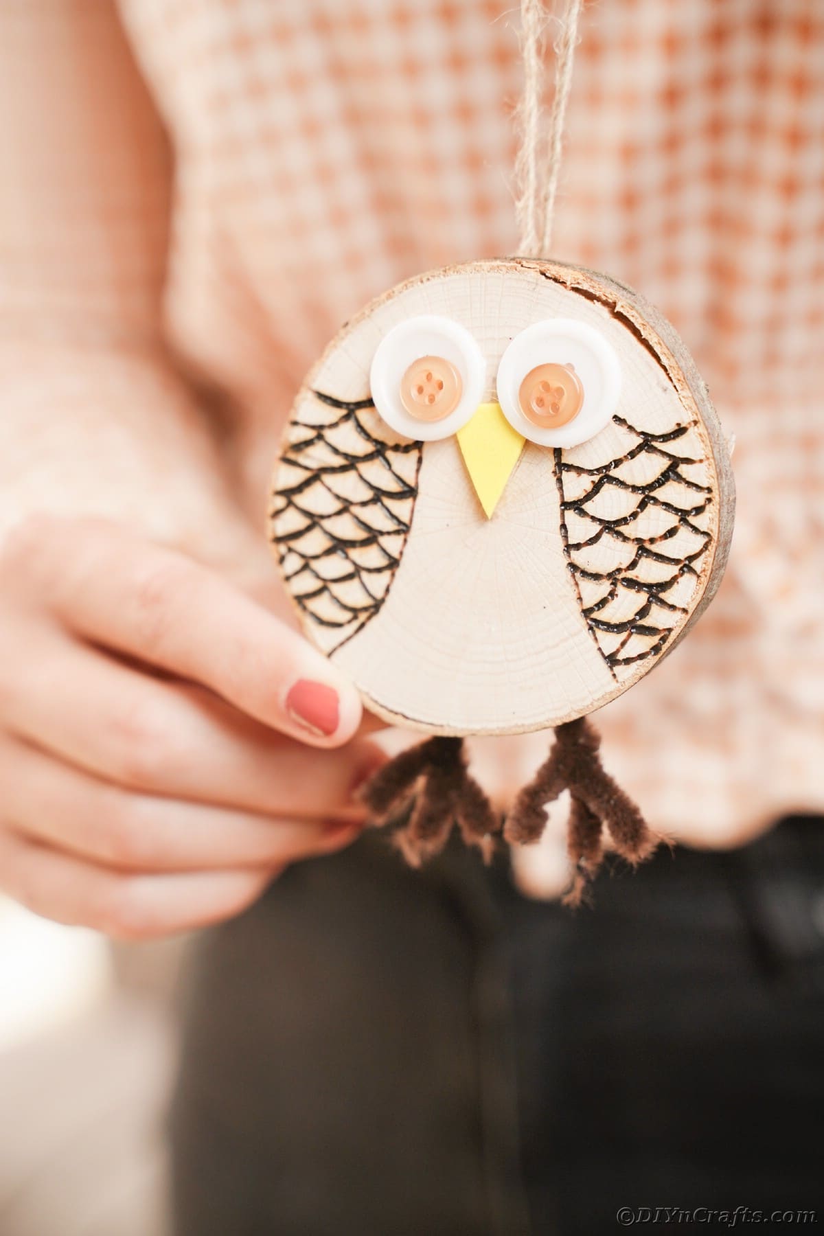 Woman in checked shirt holding wood slice owl