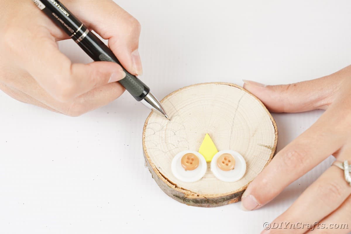 Hand mit Federzeichnung auf Holzscheibe