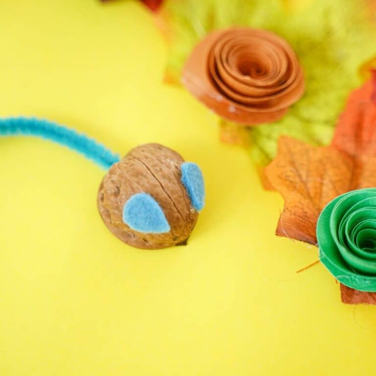 Walnut shell mouse on yellow paper with fake leaves and fake flower