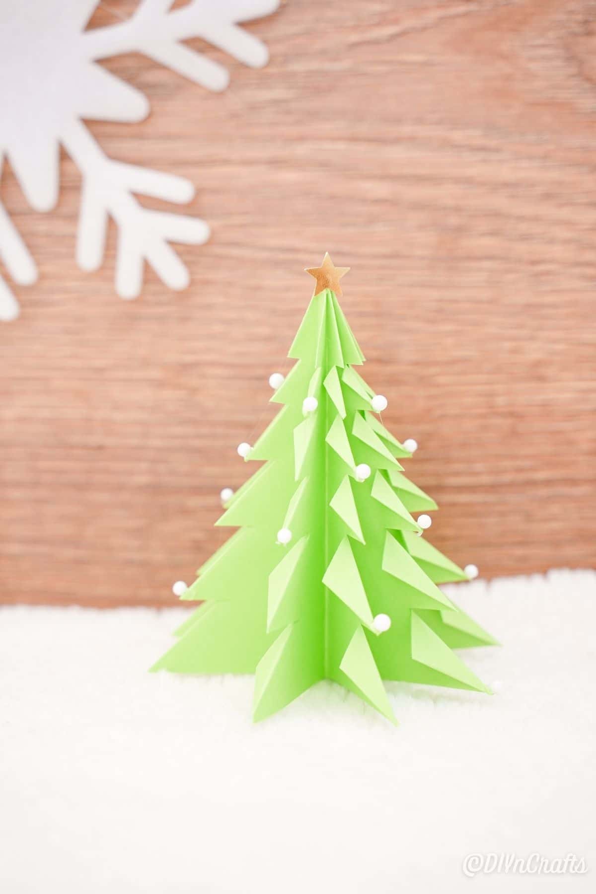 3d paper Christmas tree inf ront of wood background